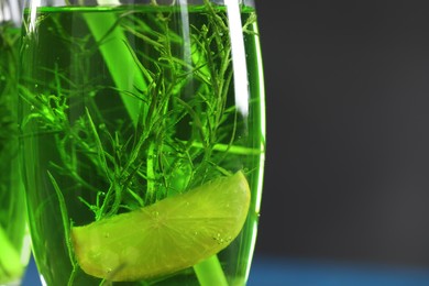 Photo of Glass of homemade refreshing tarragon drink with lemon slice, closeup