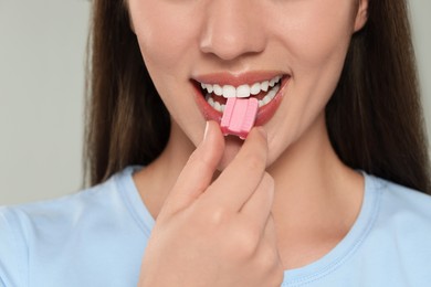 Woman with bubble gum on color background, closeup