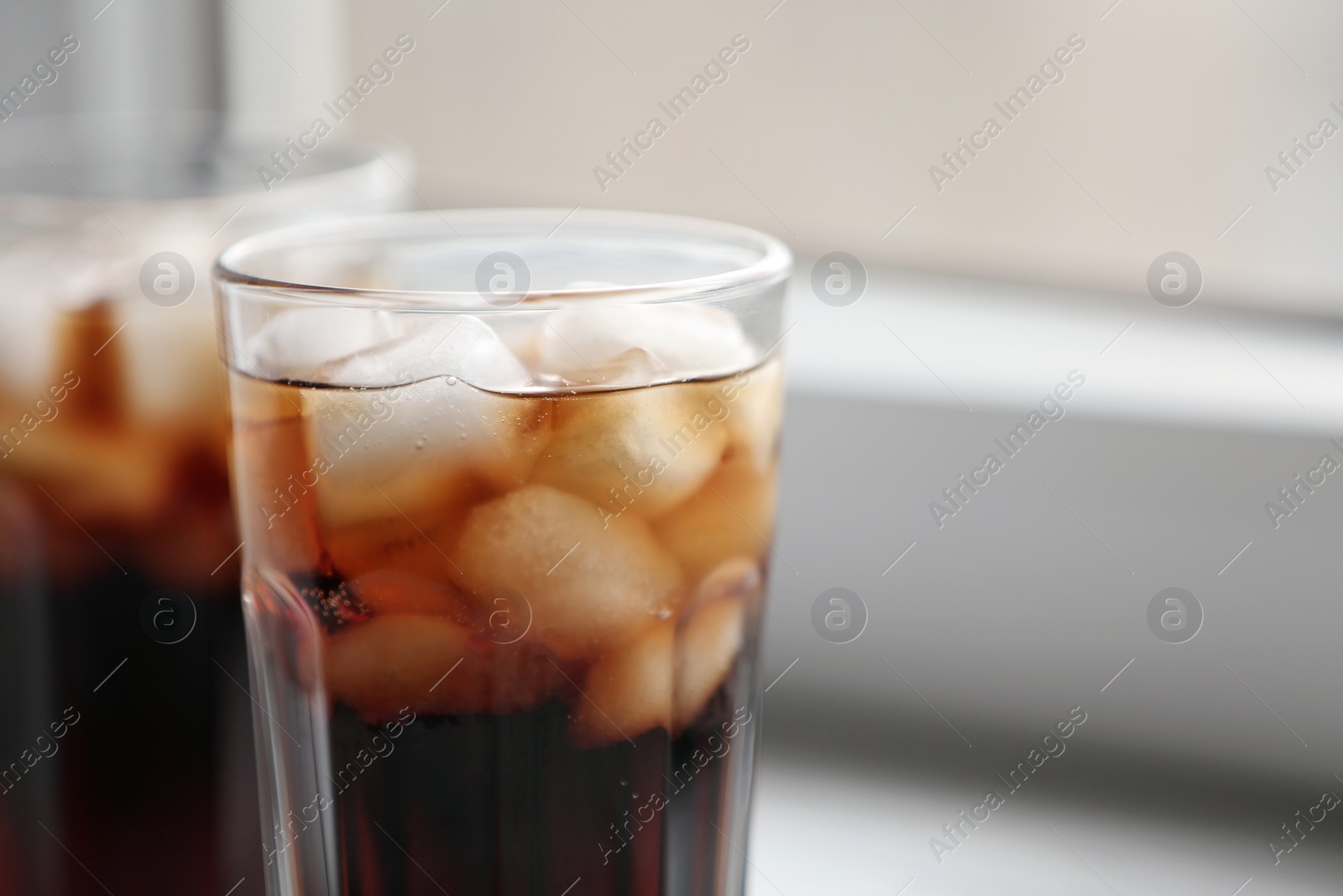 Photo of Glasses of cola with ice on blurred background, closeup. Space for text