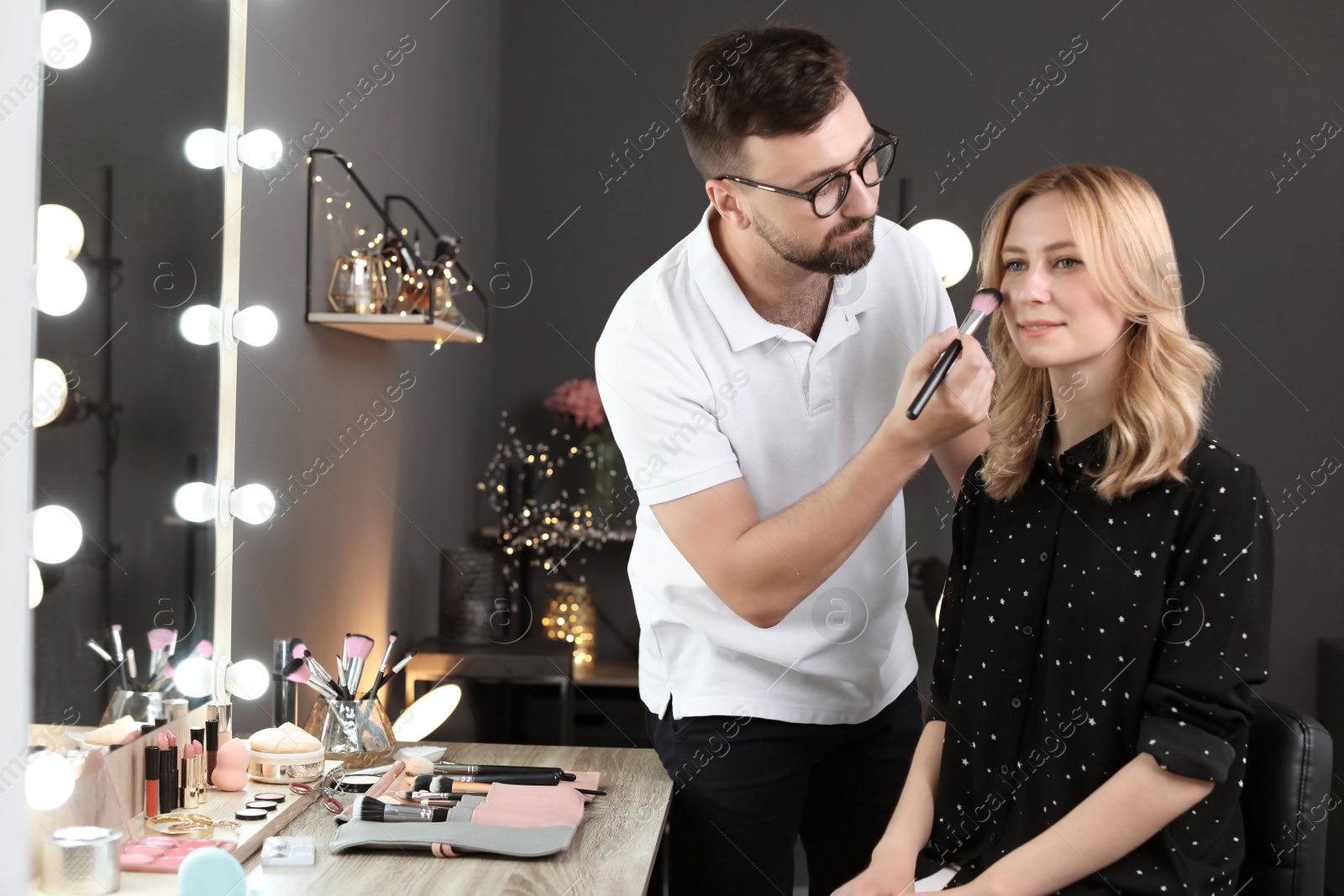 Photo of Professional makeup artist working with client in dressing room