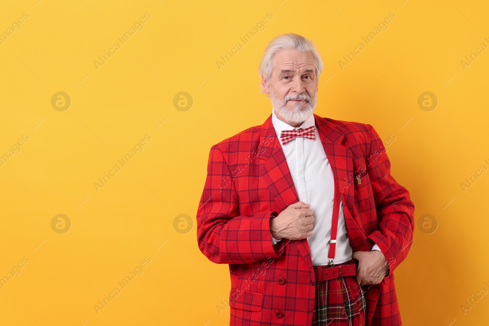 Photo of Portrait of grandpa with stylish red suit and bowtie on yellow background, space for text