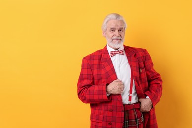 Portrait of grandpa with stylish red suit and bowtie on yellow background, space for text