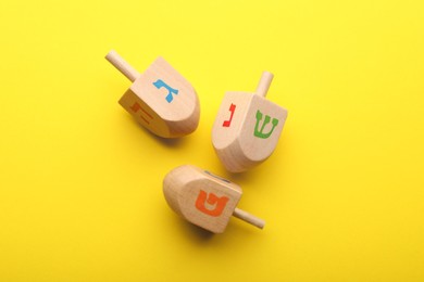 Wooden dreidels on yellow background, above view. Traditional Hanukkah game