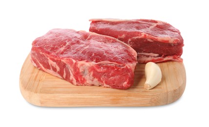 Photo of Board with steaks of raw beef meat and garlic clove isolated on white