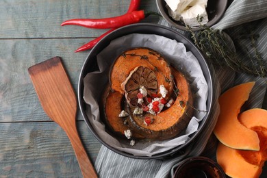 Freshly baked pumpkin slices with cheese, garlic, chili pepper and thyme on grey wooden table, flat lay