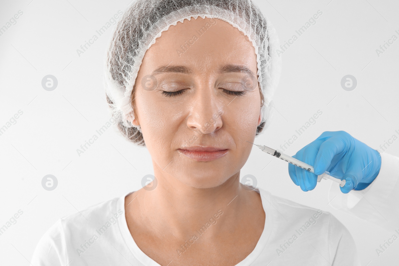 Photo of Mature woman getting facial injection on white background. Cosmetic surgery concept