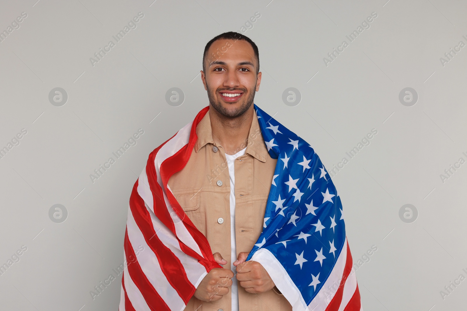 Photo of 4th of July - Independence Day of USA. Happy man with American flag on light grey background