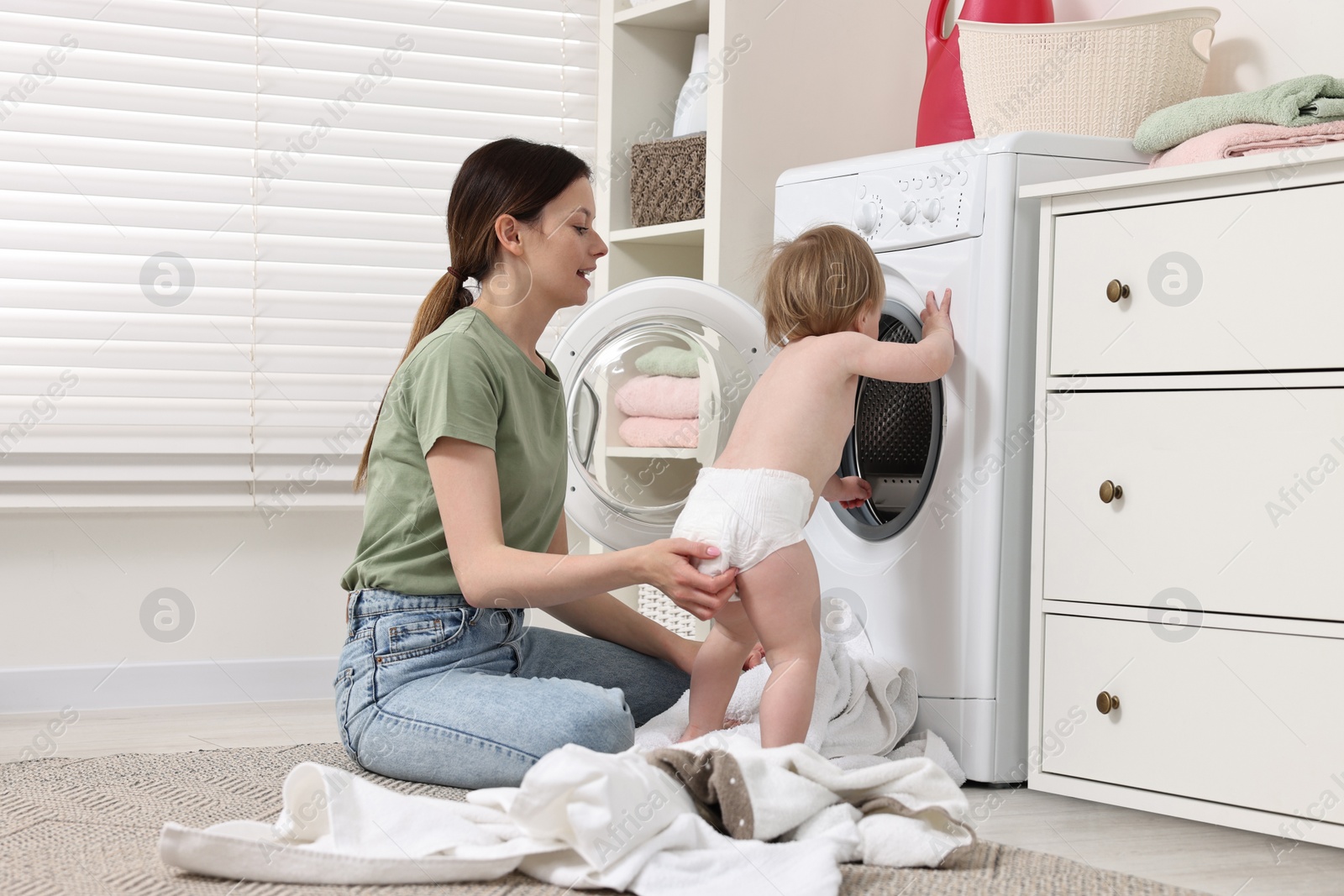 Photo of Mother with her daughter washing baby clothes in bathroom