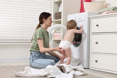 Mother with her daughter washing baby clothes in bathroom