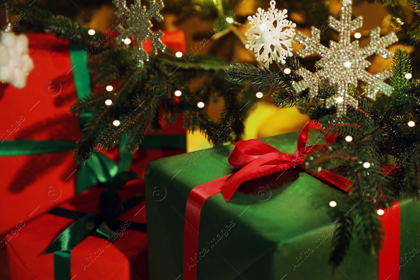 Photo of beautifully wrapped gift boxes under Christmas tree indoors, closeup