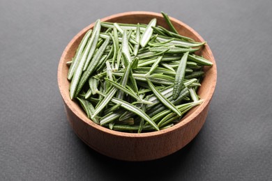 Photo of Wooden bowl of fresh green rosemary leaves on grey background