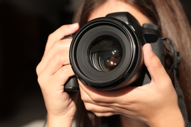 Photo of Female photographer with professional camera on dark background, closeup