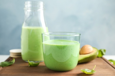 Glassware with healthy detox smoothie and spinach on table