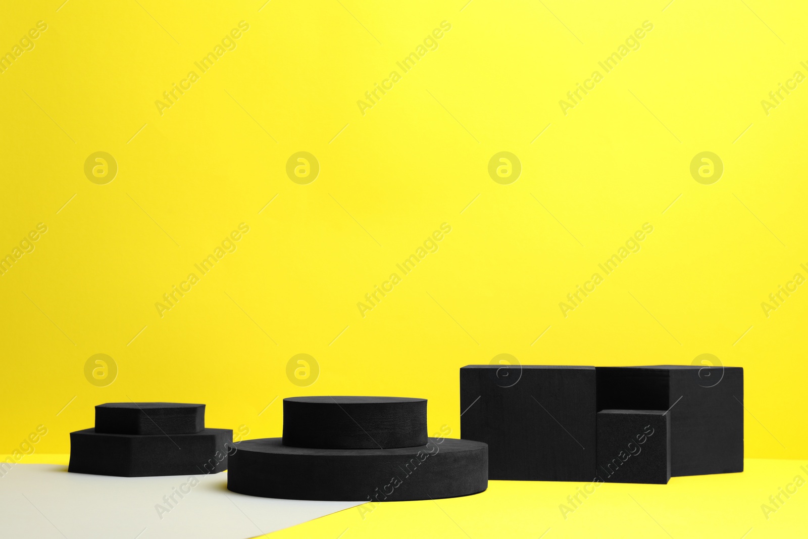 Photo of Many black geometric figures on yellow background, space for text. Stylish presentation for product