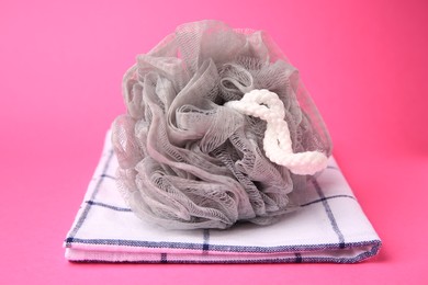 Photo of Grey shower puff and towel on pink background