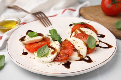 Photo of Delicious Caprese salad with balsamic vinegar on white table, closeup