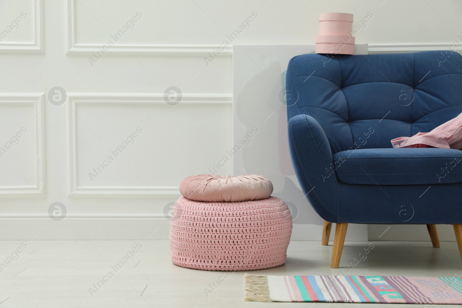 Photo of Stylish room interior with pouf, armchair and decor elements. Space for text