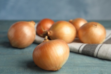 Photo of Ripe onions on blue wooden table, space for text