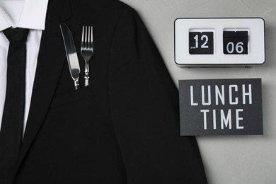 Creative business lunch layout. Men's jacket with cutlery in pocket, card and flip clock on light gray background, flat lay