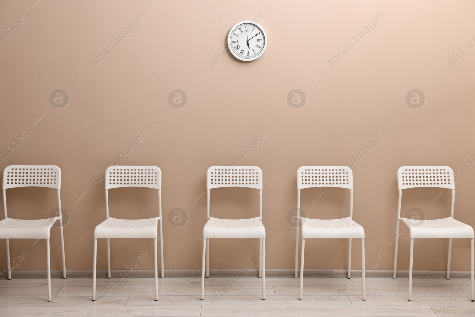 Photo of Many chairs near beige wall in waiting area indoors