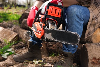 Man with modern electric saw outdoors, closeup