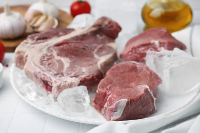 Photo of Fresh raw cut beef and ice cubes on white table, closeup