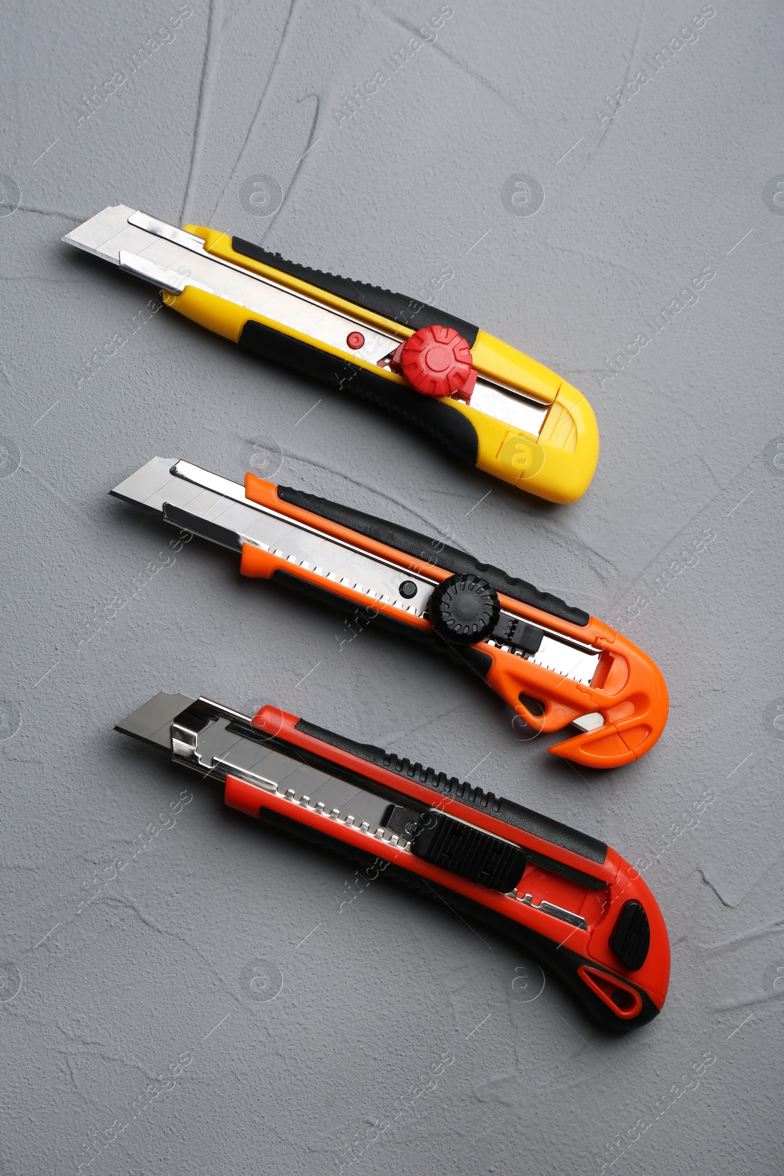 Photo of Different utility knives on grey background, flat lay