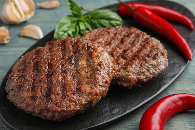 Photo of Grilled meat cutlets for burger on blue wooden table, closeup