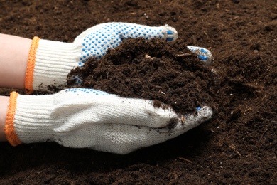 Photo of Woman holding fertile soil in hands, closeup. Gardening season