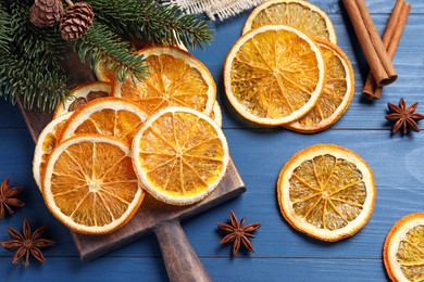 Dry orange slices, anise stars and fir tree branches on blue wooden table, flat lay