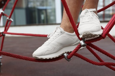 Photo of Man in stylish sneakers standing on training equipment outdoors, closeup