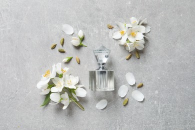 Photo of Bottle of luxury perfume and fresh jasmine flowers on light grey table, flat lay