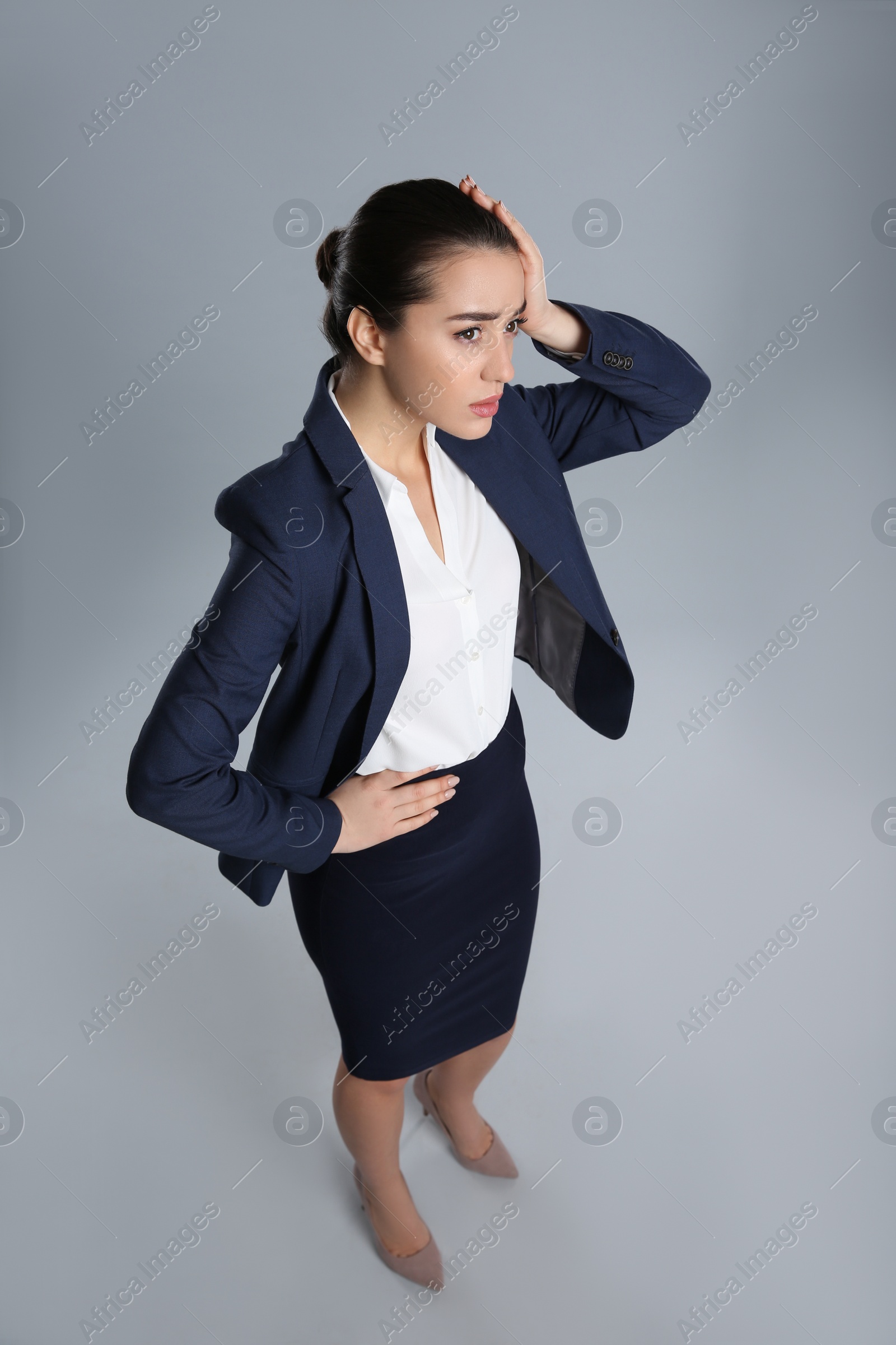 Photo of Young stressed businesswoman in elegant suit on grey background