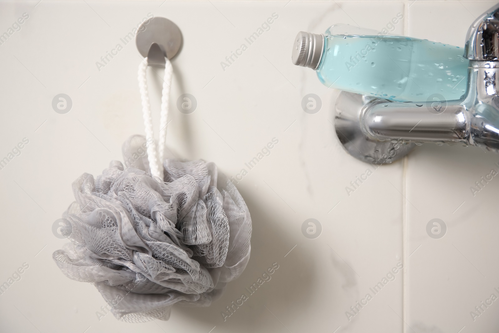 Photo of Grey shower puff and bottle of body wash gel in bathroom