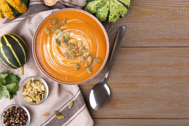 Photo of Flat lay composition with bowl of delicious pumpkin soup on wooden table. Space for text