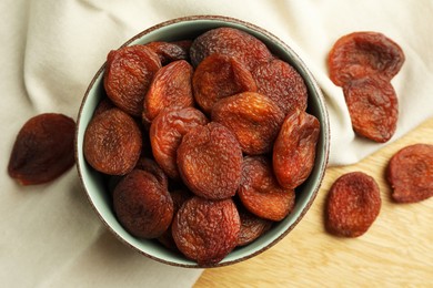 Tasty apricots with bowl on wooden table, top view. Dried fruits