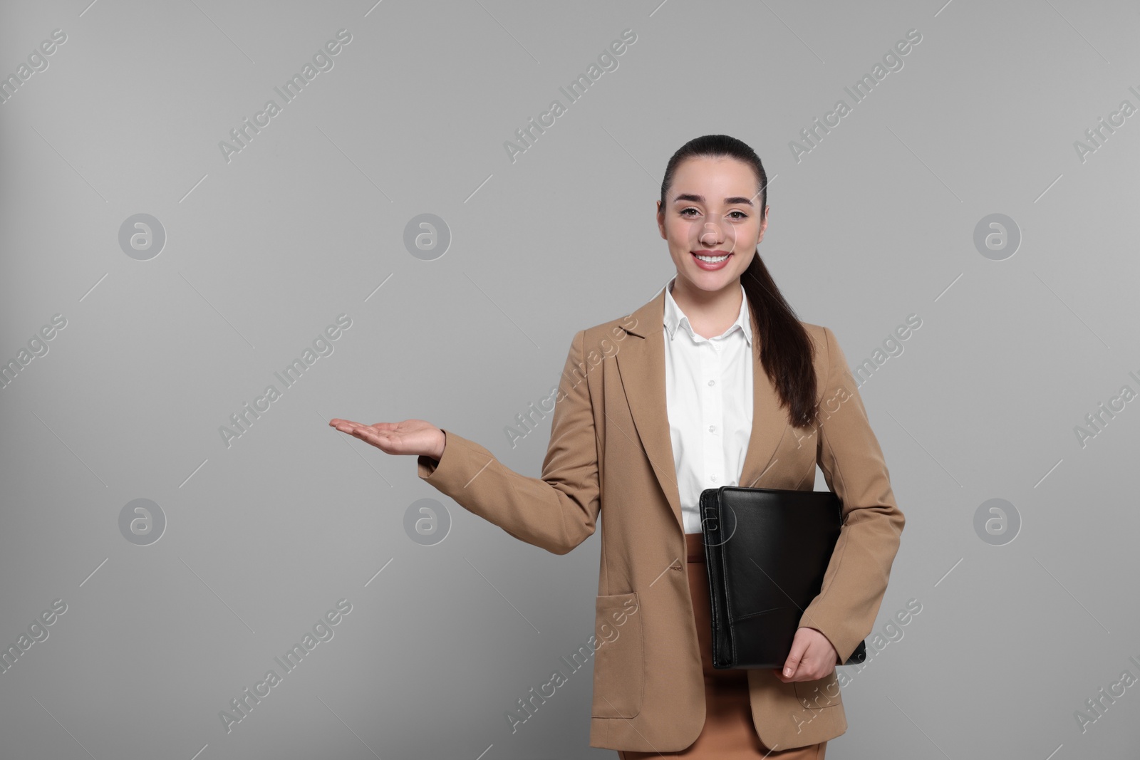 Photo of Happy real estate agent with leather portfolio on grey background. Space for text