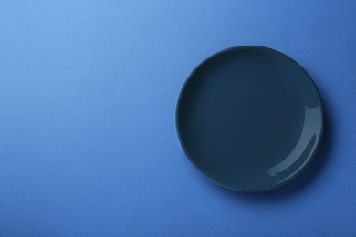 Photo of Clean plate on blue background, top view. Space for text