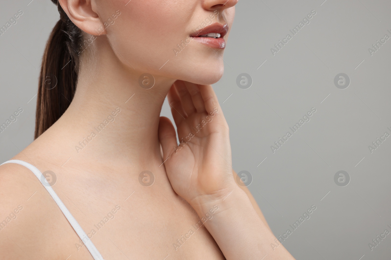 Photo of Woman touching her neck on grey background, closeup. Space for text