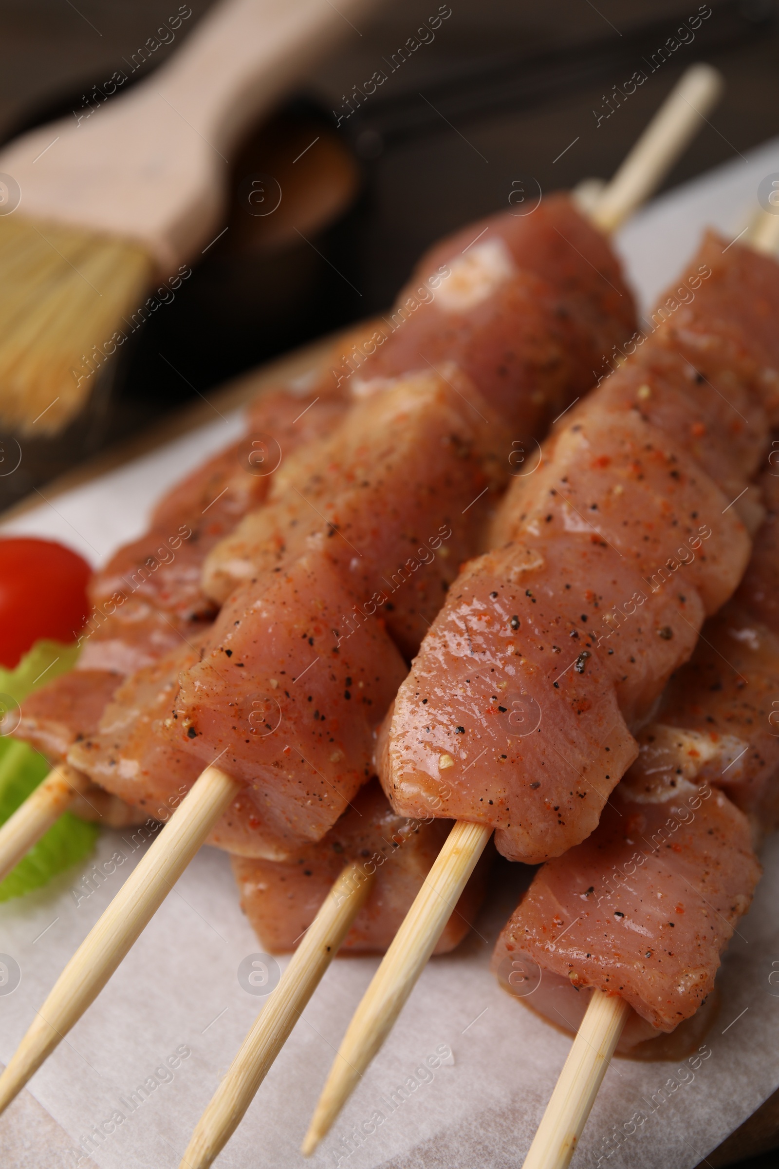 Photo of Skewers with cut raw marinated meat on wooden table, closeup