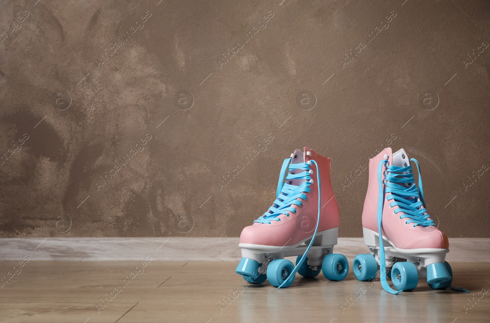 Photo of Vintage roller skates on floor near brown wall. Space for text