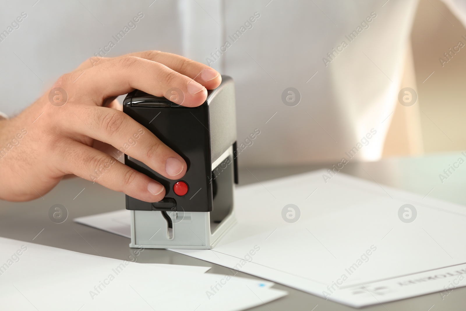 Photo of Male notary stamping document at table, closeup