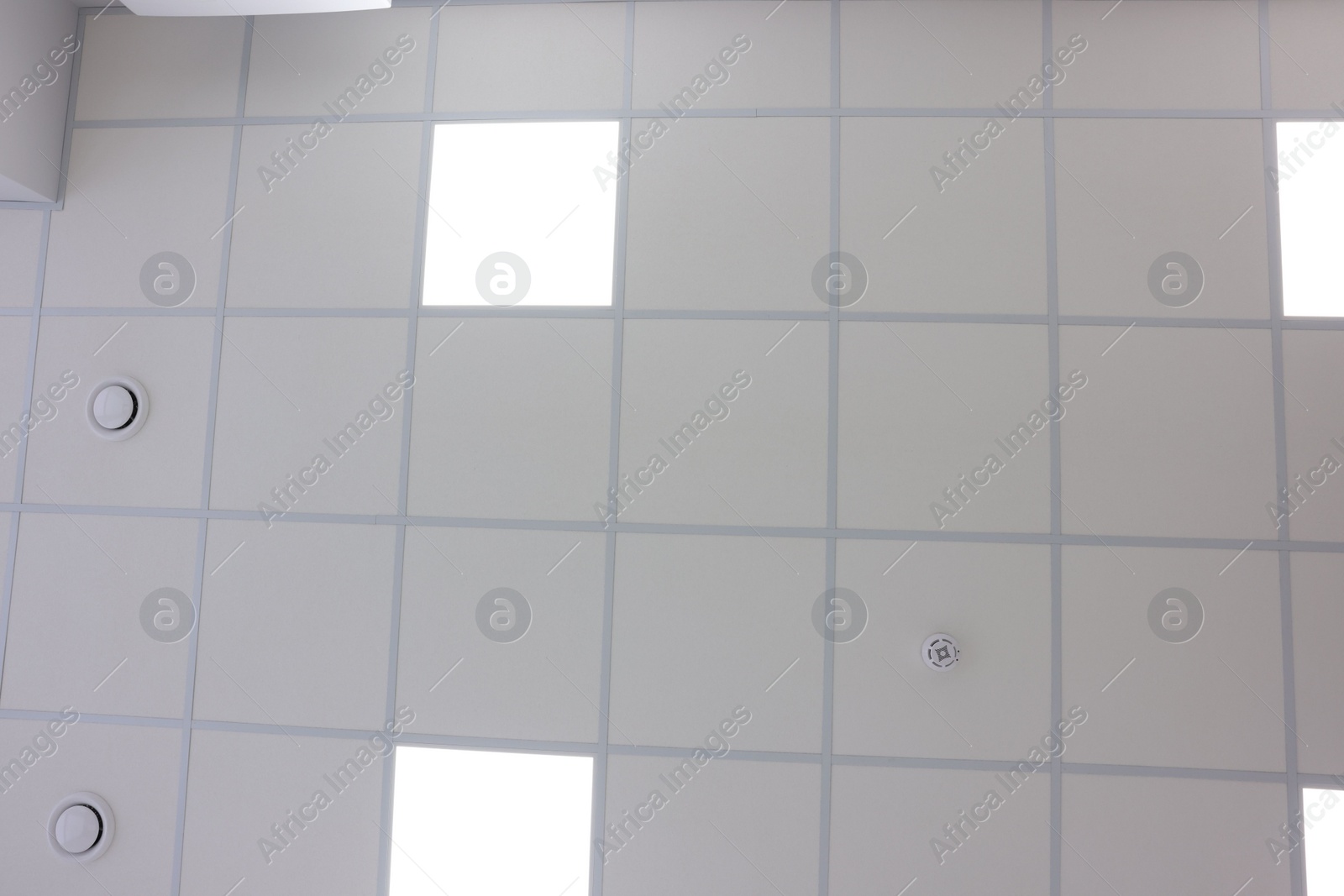 Photo of White ceiling with PVC tiles and lighting indoors, bottom view