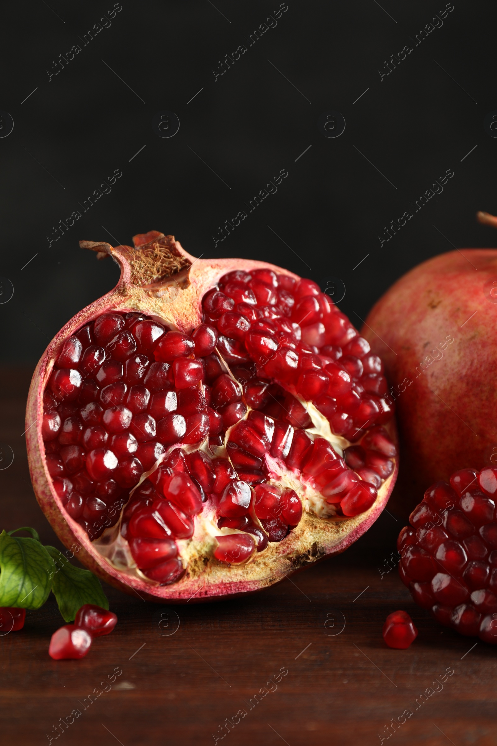 Photo of Fresh pomegranates and green leaves on wooden table