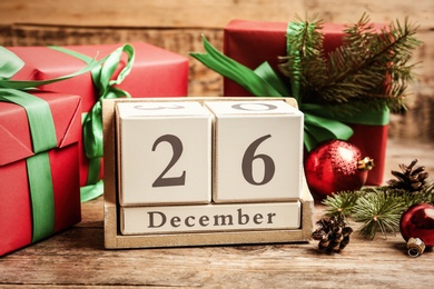 Photo of Block calendar with Boxing Day date near gifts on wooden table