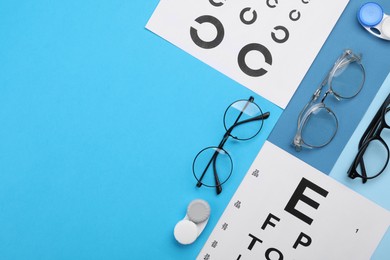 Photo of Vision test charts, glasses and lenses on light blue background, flat lay. Space for text