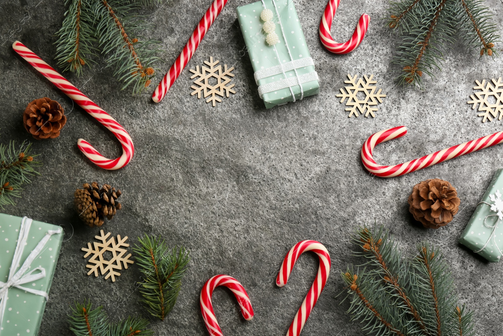 Photo of Flat lay composition with candy canes and Christmas decor on grey table. Space for text