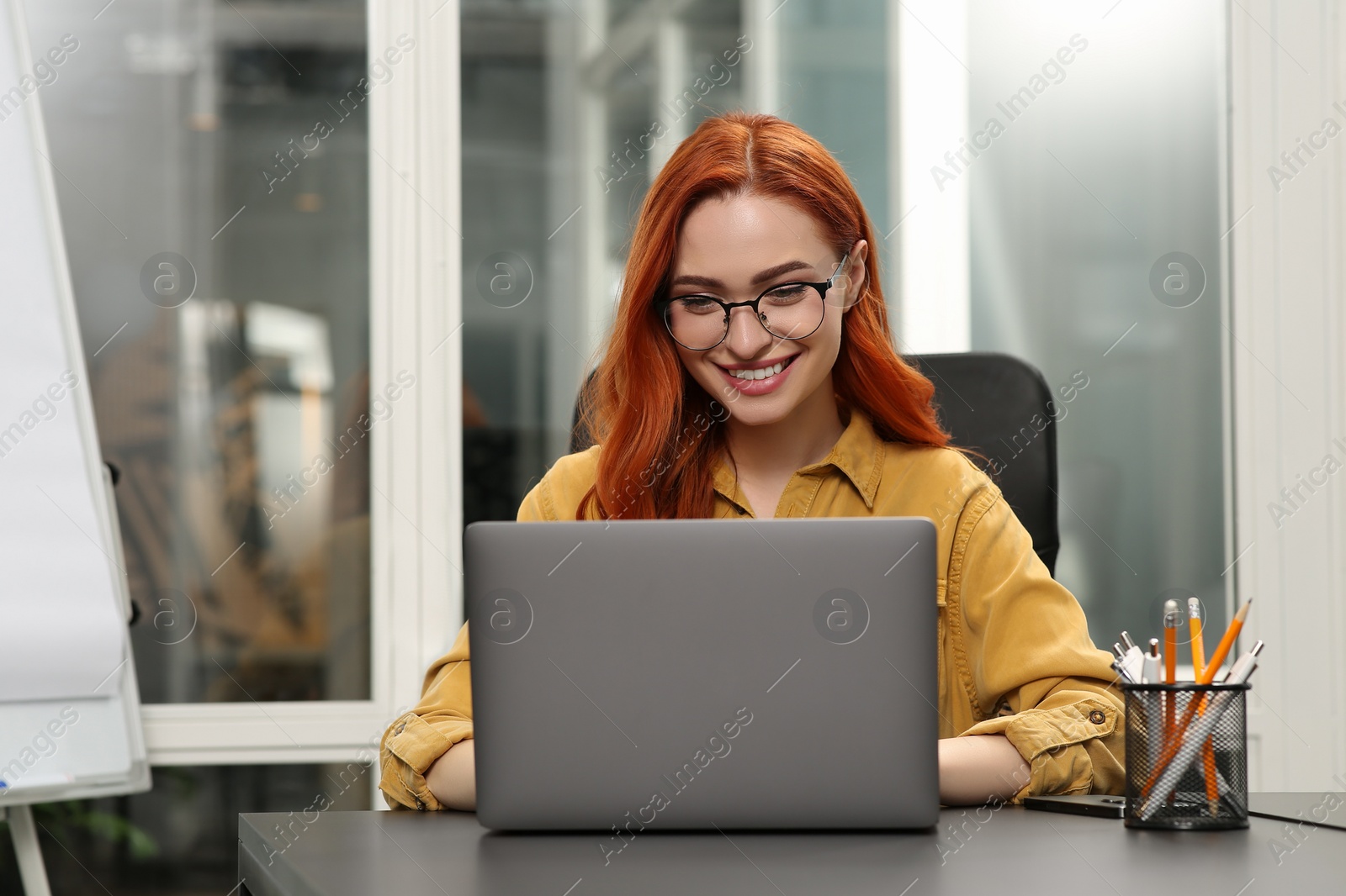 Photo of Happy woman working with laptop at desk in office