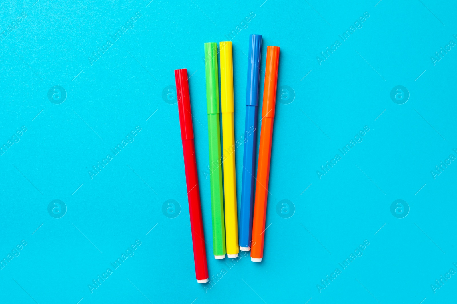 Photo of Many bright markers on light blue background, flat lay