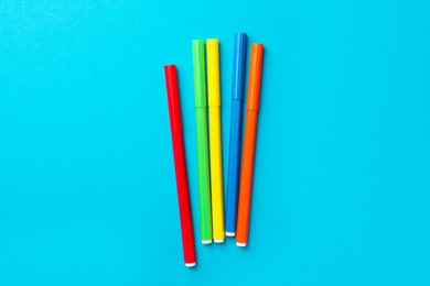 Photo of Many bright markers on light blue background, flat lay